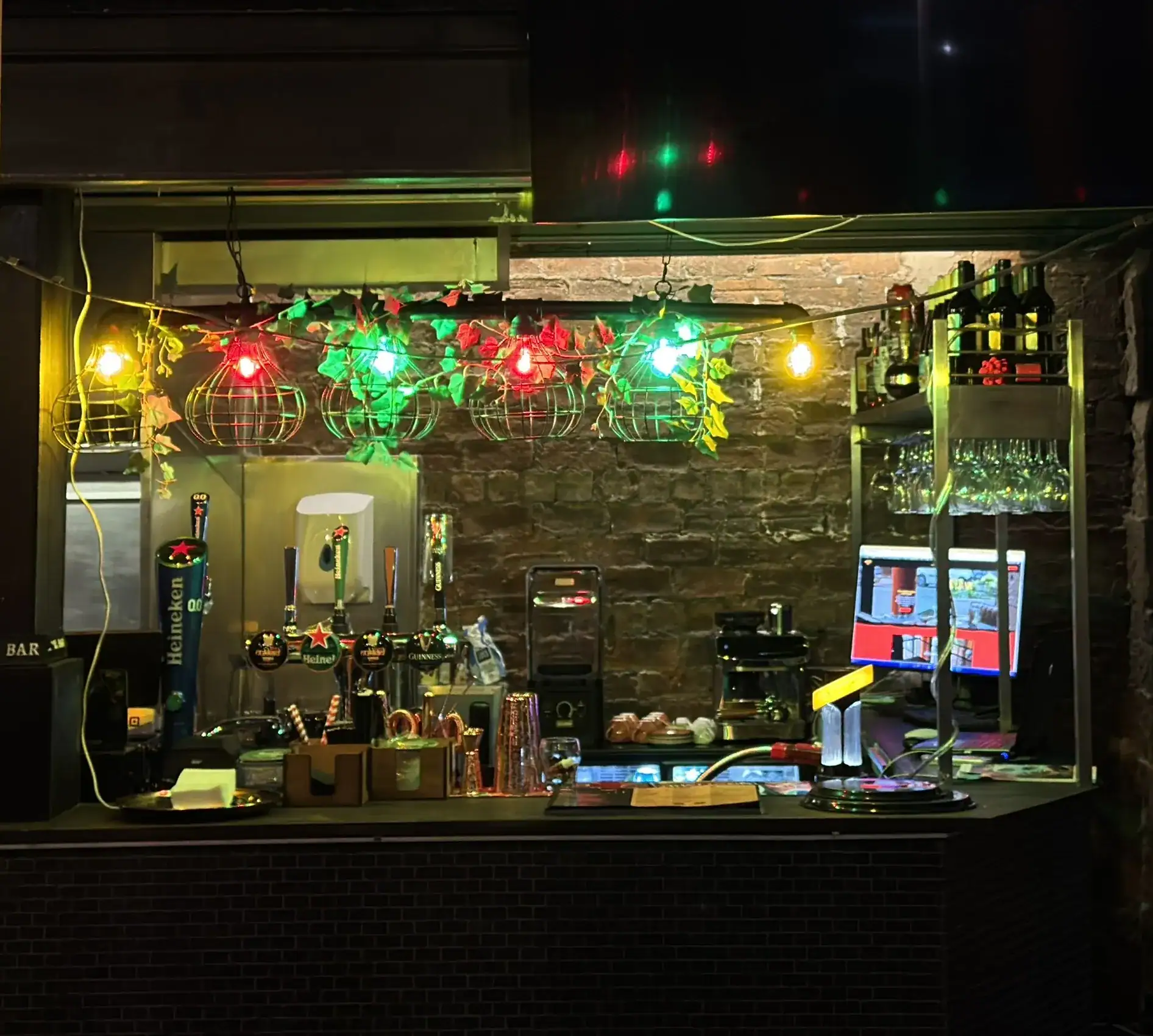 The bar counter at Nukkad Café under red, green and gold festoon lights, Merchant City, Glasgow